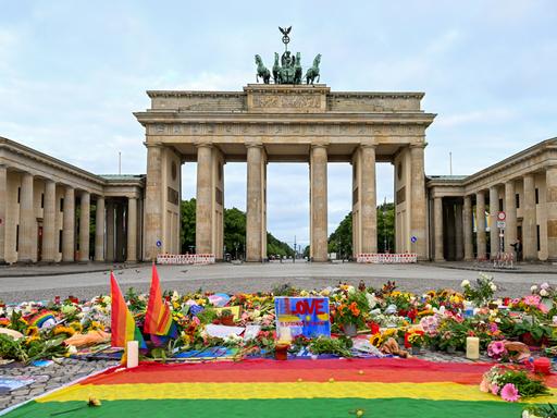 Blumen, Kerzen, Botschaften und eine Regenbogenfahne sind am Morgen auf dem Pariser Platz vor dem Brandenburger Tor zu sehen. Im Tiergarten war am Rande des Christopher Street Day ein Mann mit einem Fahrzeug in eine Menschenmenge gefahren.