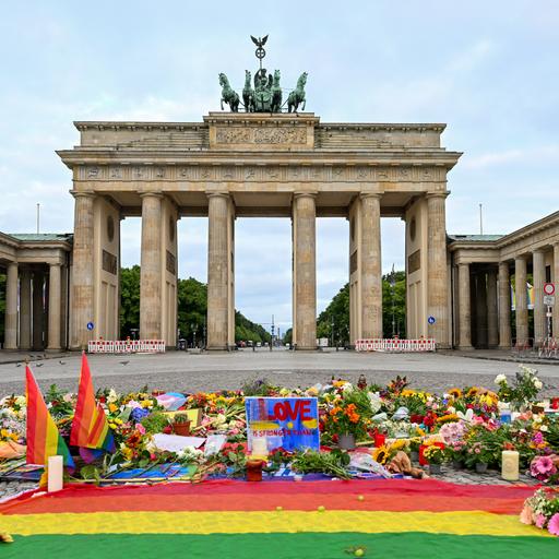 Blumen, Kerzen, Botschaften und eine Regenbogenfahne sind am Morgen auf dem Pariser Platz vor dem Brandenburger Tor zu sehen. Im Tiergarten war am Rande des Christopher Street Day ein Mann mit einem Fahrzeug in eine Menschenmenge gefahren.