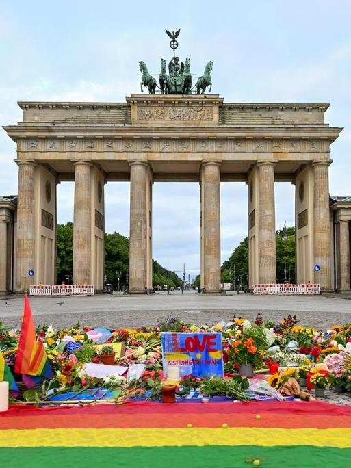 Blumen, Kerzen, Botschaften und eine Regenbogenfahne sind am Morgen auf dem Pariser Platz vor dem Brandenburger Tor zu sehen. Im Tiergarten war am Rande des Christopher Street Day ein Mann mit einem Fahrzeug in eine Menschenmenge gefahren.