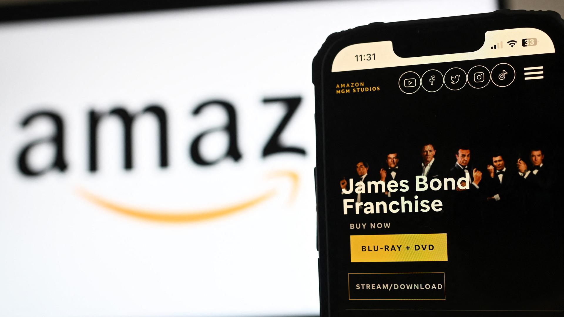 Das Bild zeigt die Website der MGM Studios Details zum James Bond-Franchise auf einem Telefonbildschirm neben einem Amazon-Logo auf einem Laptop-Bildschirm.