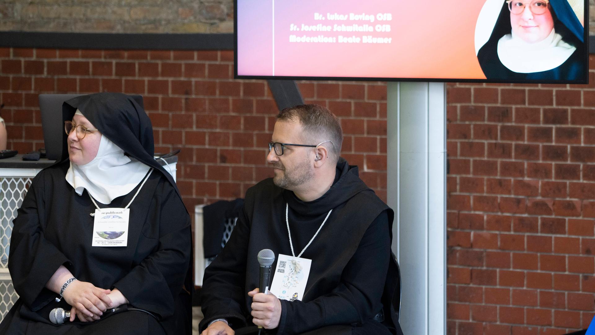 Ordensschwester Josefine Schwitalla und Ordensbruder Lukas Boving sitzen vor einer Leinwand und diskutieren auf der Digitalkonferenz re:publica26 mit Teilnehmern über Mönche, Nonnen und Social Media.