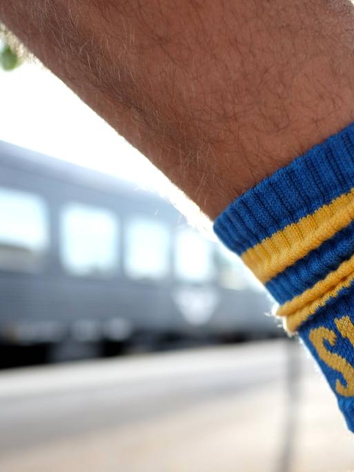 Bahnurlaub in Schweden. Socken in schwedischen Farben und mimit SWE Schriftzug vor einem Wagen der schwedischen Eisenbahngesellschaft SJ  in Emmaboda.