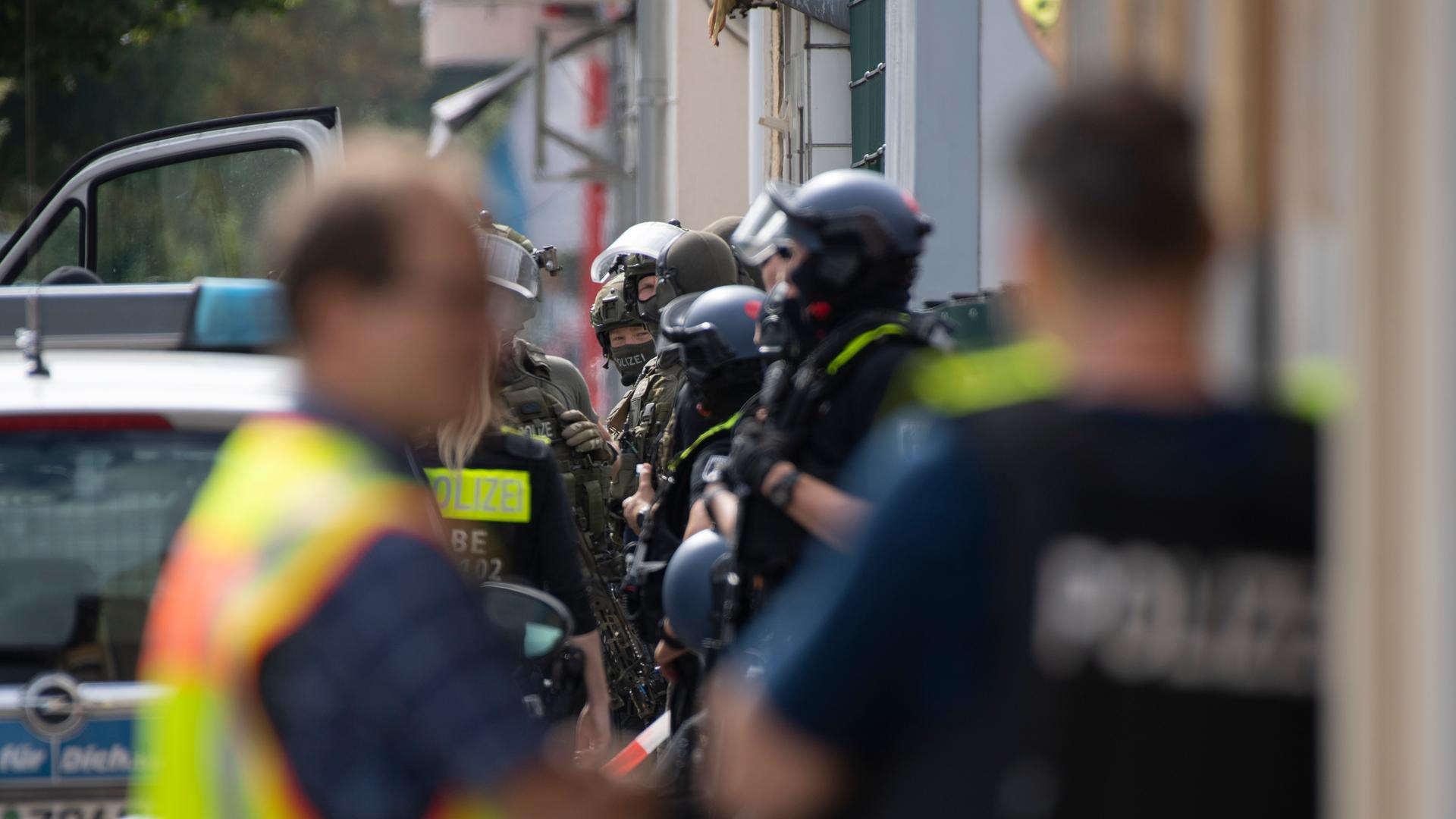 Bewaffnete Polizeikräfte stehen an einer Straße in Berlin. Sie haben zum Teil Schutzhelme auf und tragen schusssichere Westen. Bewaffnete Polizeikräfte stehen an einer Straße in Berlin. Sie haben zum Teil Schutzhelme auf und tragen schusssichere Westen.