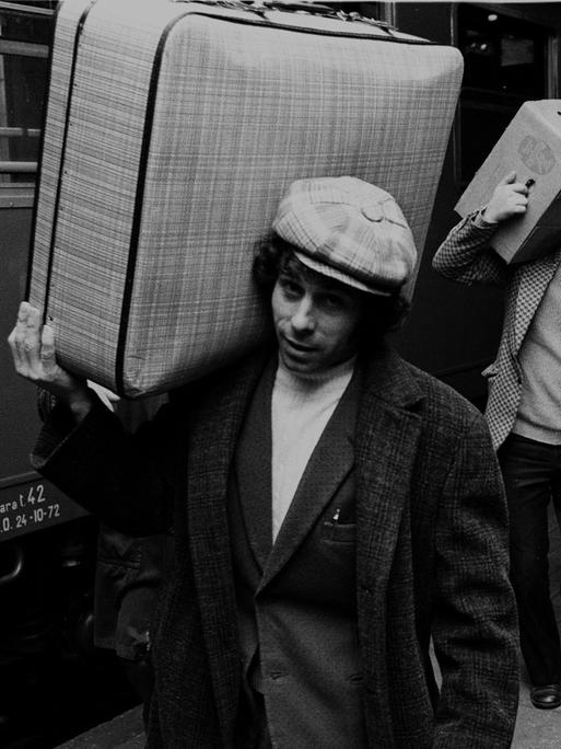 Italienische Gastarbeiter, bei VW in Wolfsburg beschäftigt, fahren in den Weihnachtsurlaub Richtung Italien - hier am 16.12.1972 vom Wolfsburger Bahnhof. Ein Mann mit Locken und Schirmmütze trägt seinen Koffer lässig auf der Schulter.