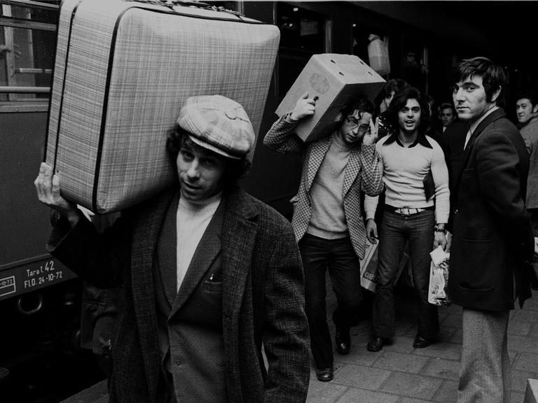 Italienische Gastarbeiter, bei VW in Wolfsburg beschäftigt, fahren in den Weihnachtsurlaub Richtung Italien - hier am 16.12.1972 vom Wolfsburger Bahnhof. Ein Mann mit Locken und Schirmmütze trägt seinen Koffer lässig auf der Schulter.