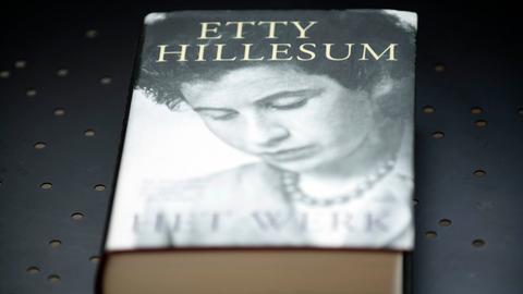 Ein Buch von Etty Hillesum liegt auf einem Tisch. Auf dem Cover zeigt es ihr Porträt in Schwarzweiß.