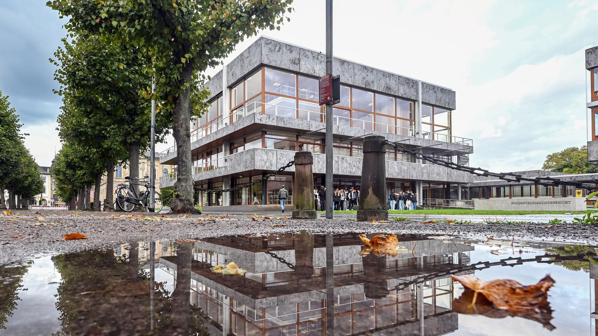 Das Bundesverfassungsgericht in Karlsruhe spiegelt sich in einer Pfütze wider. 