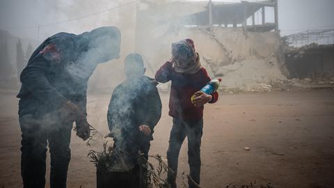Drei Menschen verbrennen Müll in einer Feuertonne, um sich zu wärmen, in Idlib, Syrien.