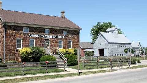Frontansicht eine Hauses in den Amana Kolonien in Iowa. An dem gemauerten Steinhaus steht "Amana Colonies Antiques".