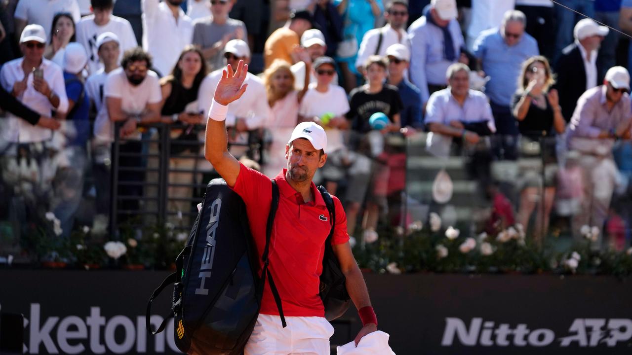 Novak Djokovic ist in der dritten Runde ausgeschieden; der Weltranglistenerste verlässt den Platz in Rom und winkt mit der rechten Hand. Er trägt ein rotes Polohemd, eine weiße Hose und hat seine Tasche über die Schulter gehängt.