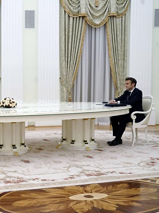 Putin und Macron sitzen an einem sehr langen Tisch in Moskau.