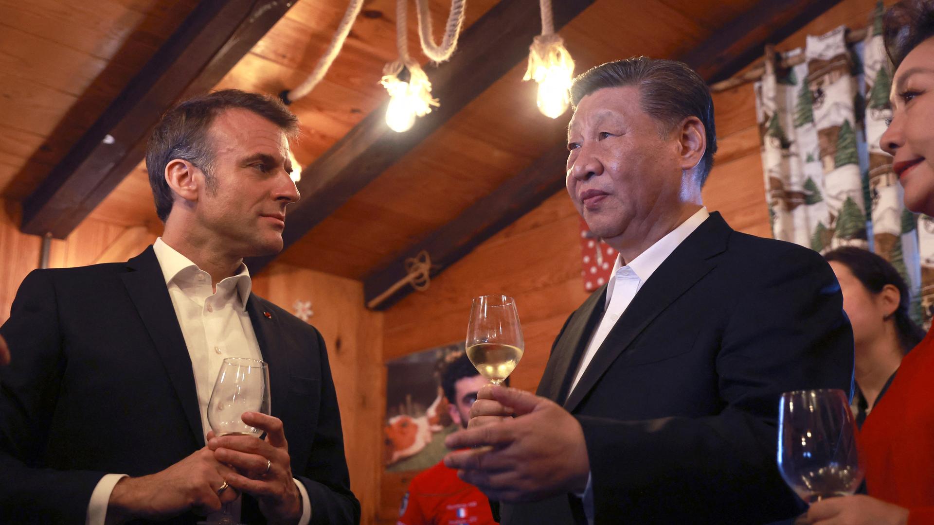Emmanuel Macron und Xi Jinping stehen bei einem Glas Wein zusammen.