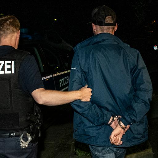 Ein Polizist führt einen Mann ab. (Archivbild)