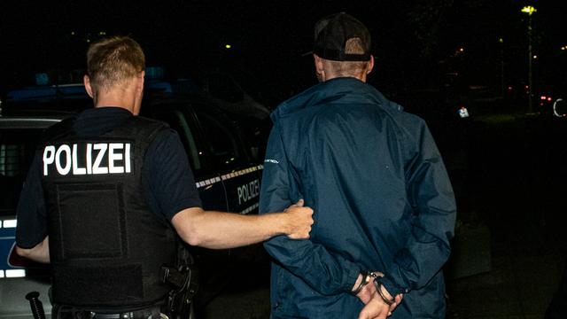 Ein Polizist führt einen Mann ab. (Archivbild)