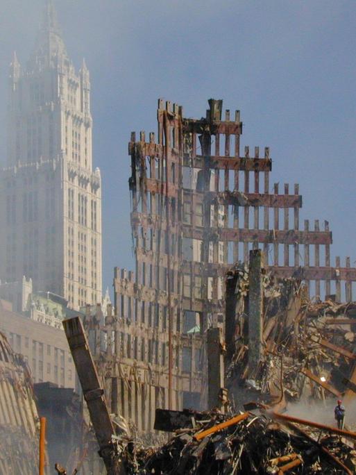 Hinter den Trümmern des World Trade Centers ist das Woolworth Building in New York zu erkennen. Dahinter blauer Himmel.