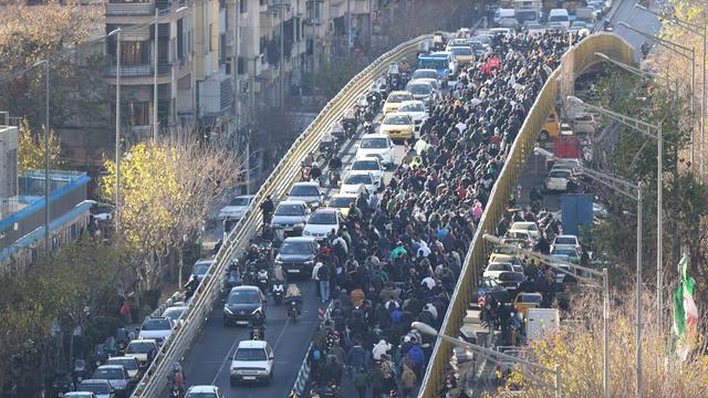 Ladenbesitzer und Händler überqueren während einer Protestaktion in der iranischen Hauptstadt Teheran eine Brücke.