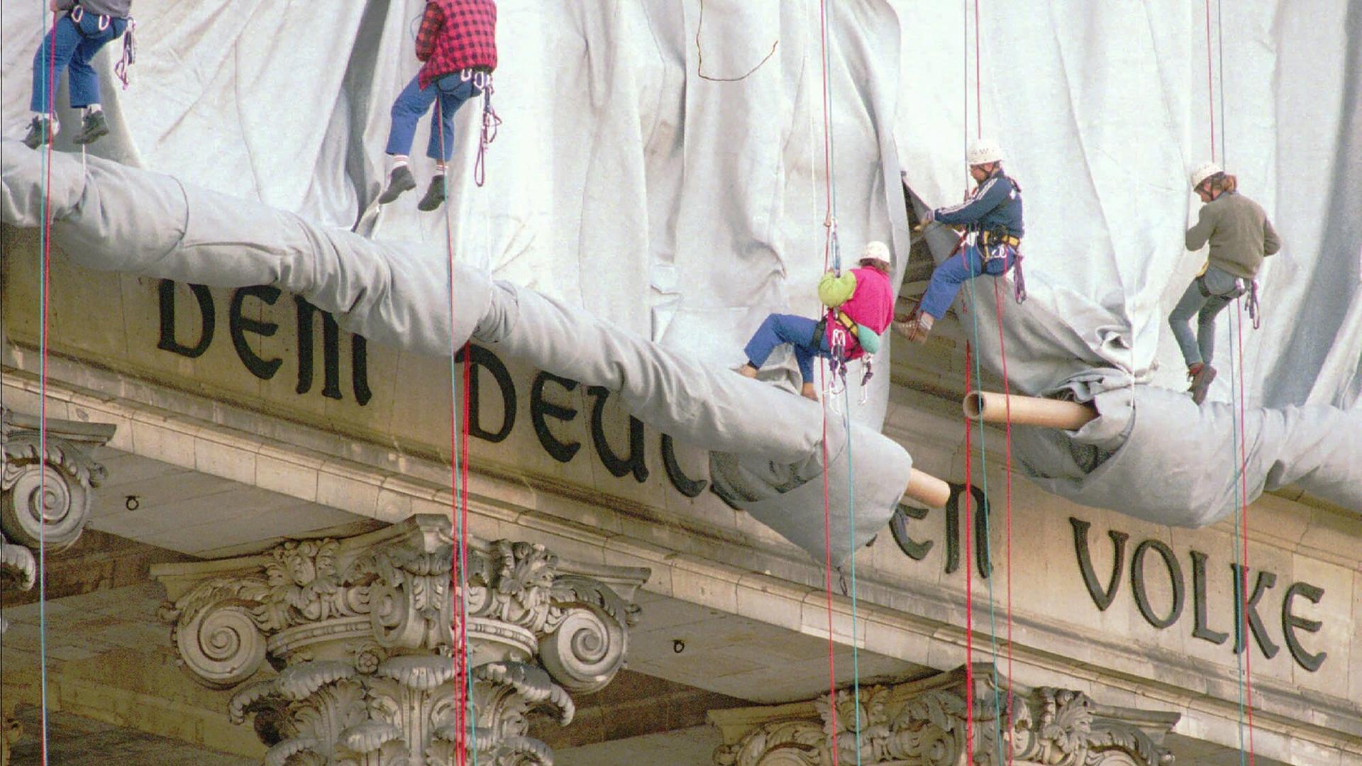Fassadenkletterer lassen silberfarbenen Stoff am Reichstagsgebäude über die Inschrift "Dem deutschen Volke" runter