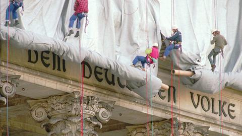 Fassadenkletterer lassen silberfarbenen Stoff am Reichstagsgebäude über die Inschrift "Dem deutschen Volke" runter