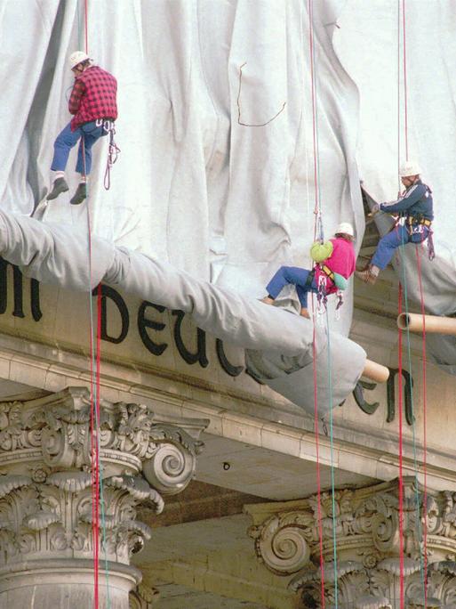 Fassadenkletterer lassen silberfarbenen Stoff am Reichstagsgebäude über die Inschrift "Dem deutschen Volke" runter