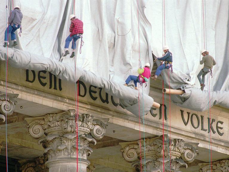 Fassadenkletterer lassen silberfarbenen Stoff am Reichstagsgebäude über die Inschrift "Dem deutschen Volke" runter