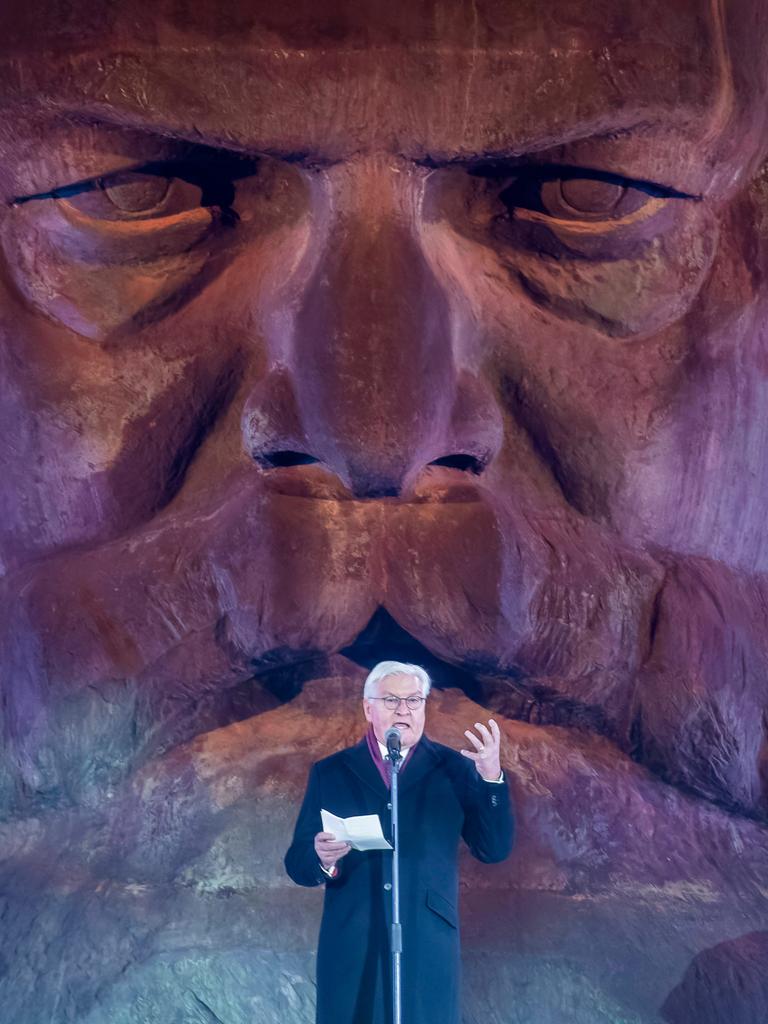 Bundespräsident Frank-Walter Steinmeier steht auf einer Bühne, hinter ihm ist ein großer Kopf aus Stein. Es ist das Karl-Marx-Denkmal in Chemnitz.