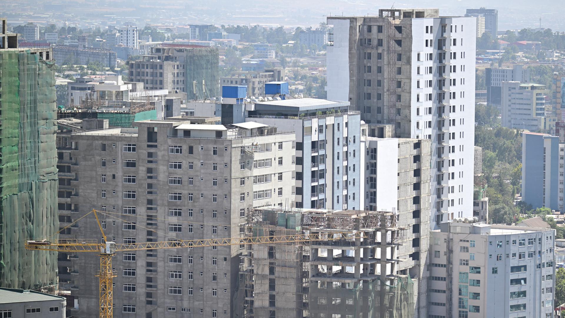 Ein Baukran steht vor teilweise fertig gestellten Hochhäusern.