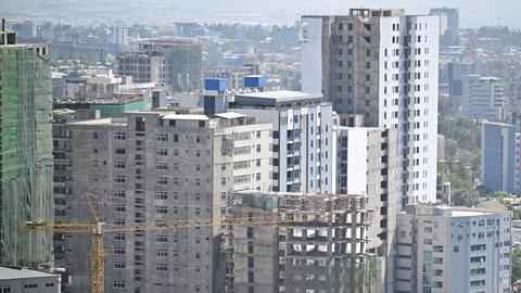 Ein Baukran steht vor teilweise fertig gestellten Hochhäusern.