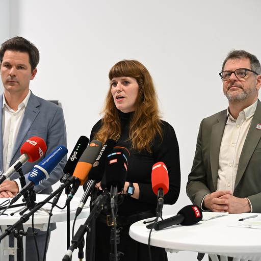 Steffen Krach, Fraktionsvorsitzender der SPD im Berliner Abgeordnetenhaus (links), Kerstin Wolter (Die Linke, Mitte) und Werner Graf, Co-Vorsitzender der Grünen-Fraktion (rechts) stehen gemeinsam an einem Tisch. Vor ihnen stehen viele Mikrofone.