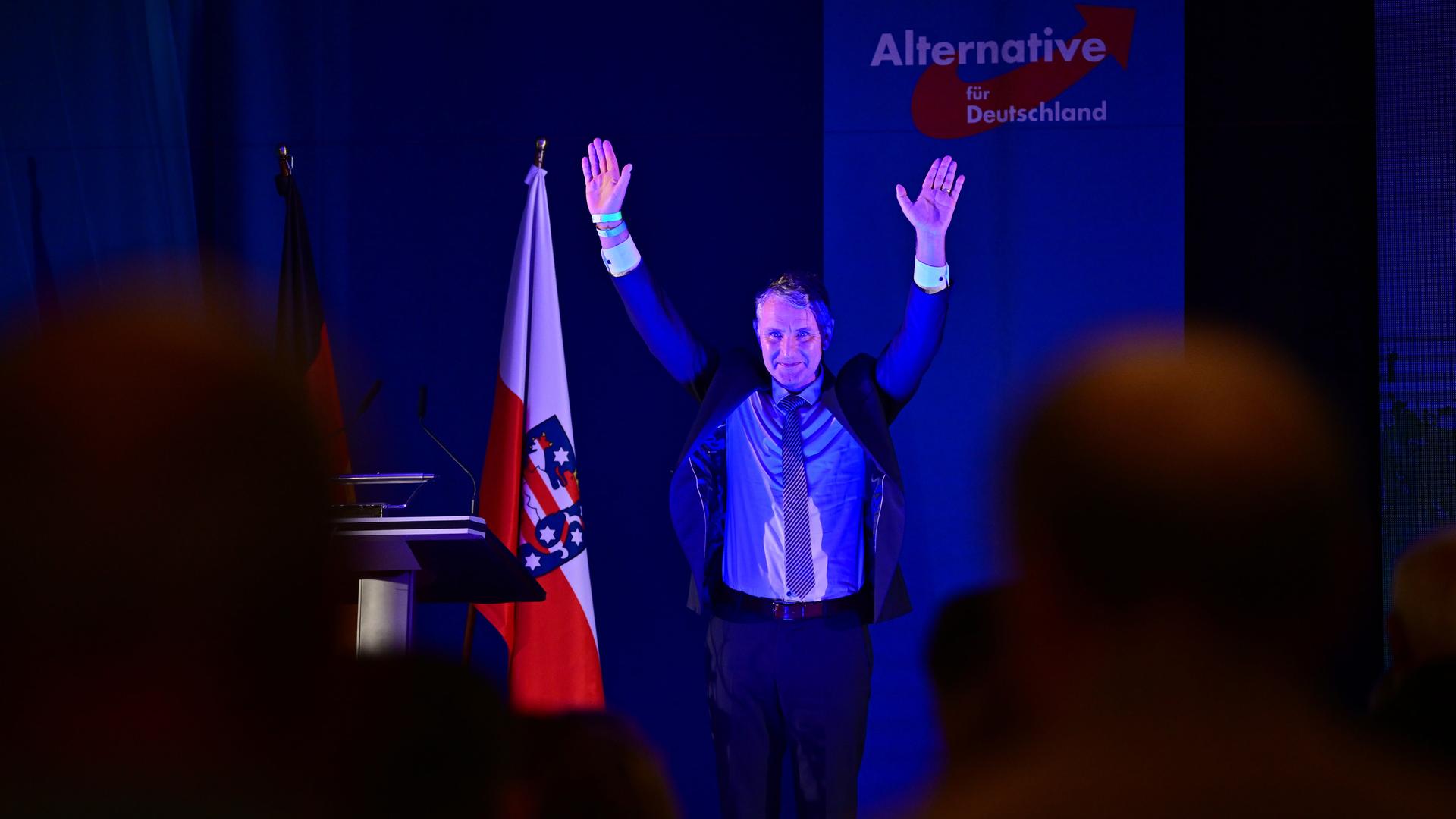 Björn Höcke, AfD-Landeschef, steht mit hochgehobenen Händen auf einer Bühne während der AfD-Veranstaltung.