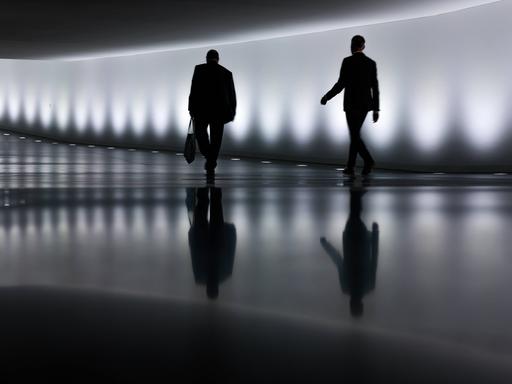 Zwei Personen im Anzug gehen im Bundestag einen Tunnel entlang. 