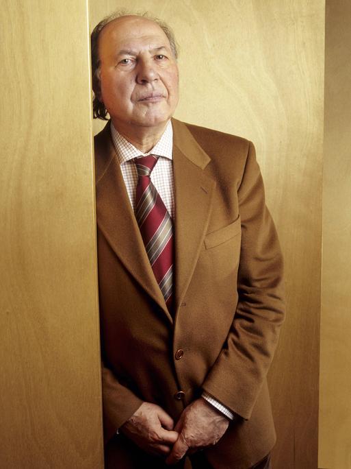 Imre Kertesz lehnt an einer holzvertäfelten Wand und blickt ernst in die Kamera Imre Kertesz lehnt an einer holzvertäfelten Wand und blickt ernst in die Kamera