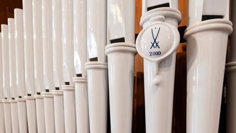 Blick auf weiß glänzende Pfeifen aus Meißner Porzellan mit dem typischen Doppel-Schwert-Symbol.