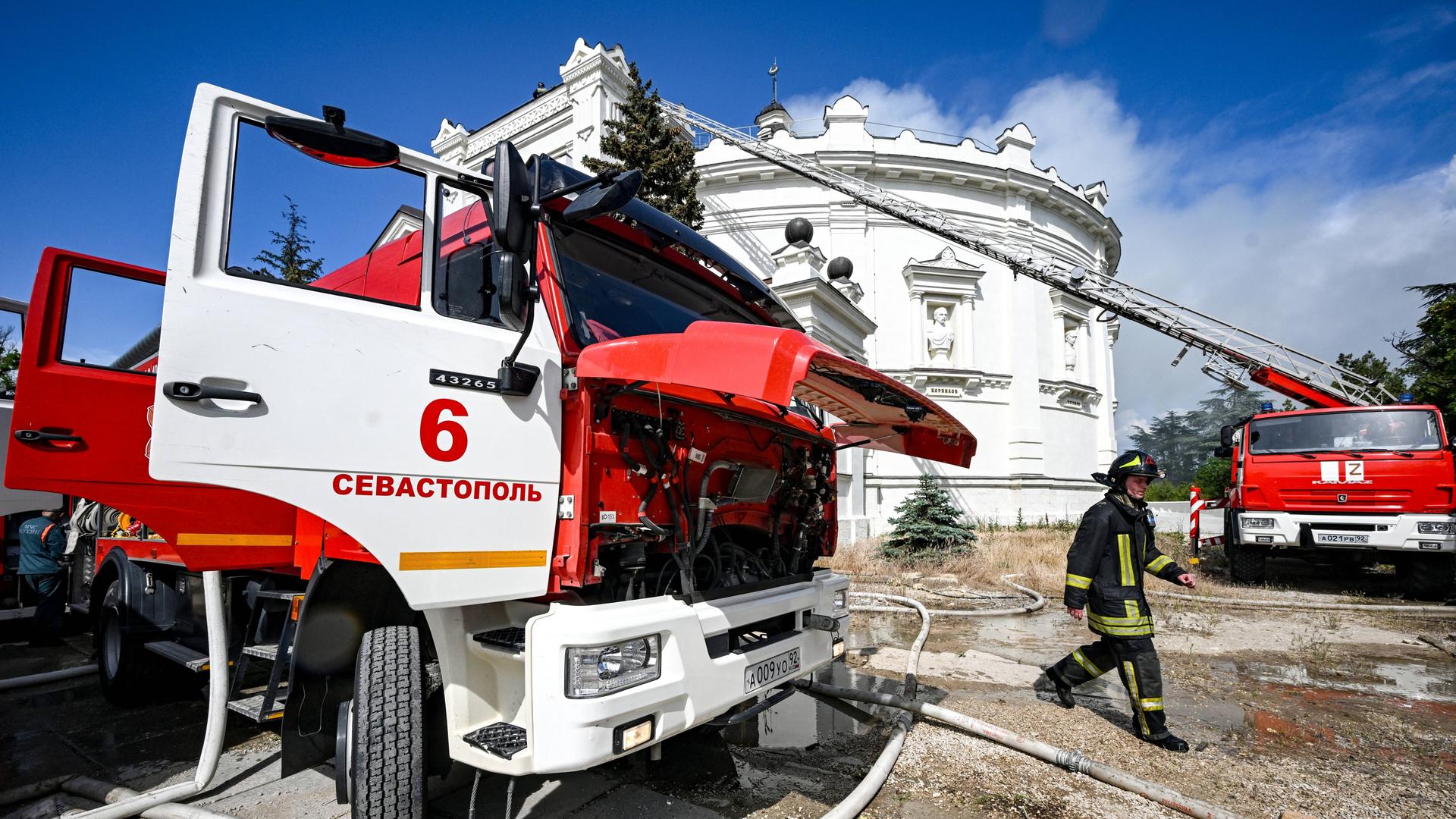 Ein klassizistisches Gebäude, davor ein Feuerwehrauto und Feuerwehrleute.