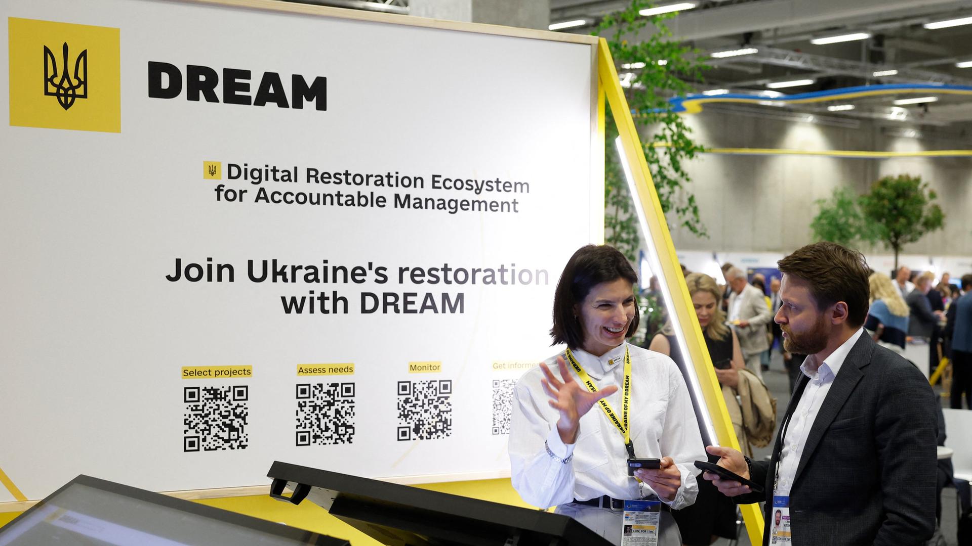 Menschen in einer Ausstellungshalle, in der über Geschäftsmöglichkeiten in der Ukraine informiert wird. 