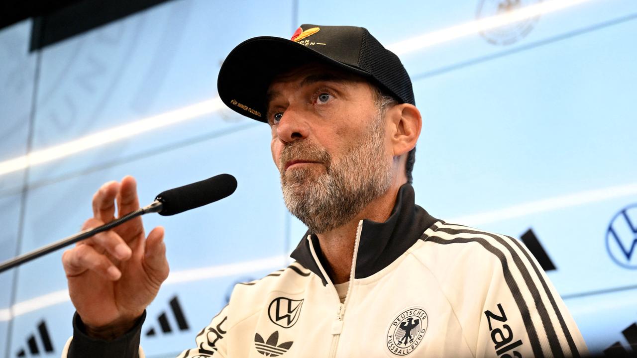Bundestrainer Jürgen Klopp sitzt auf dem Podium und spricht in ein Mikrofon.