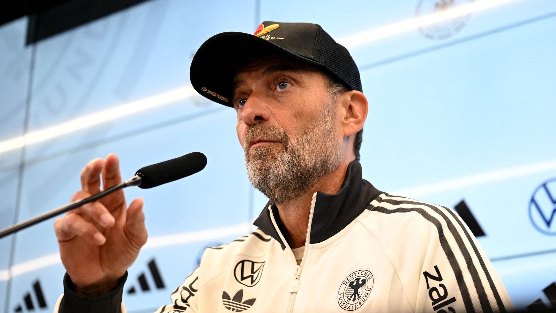 Bundestrainer Jürgen Klopp sitzt auf dem Podium und spricht in ein Mikrofon. Bundestrainer Jürgen Klopp sitzt auf dem Podium und spricht in ein Mikrofon.