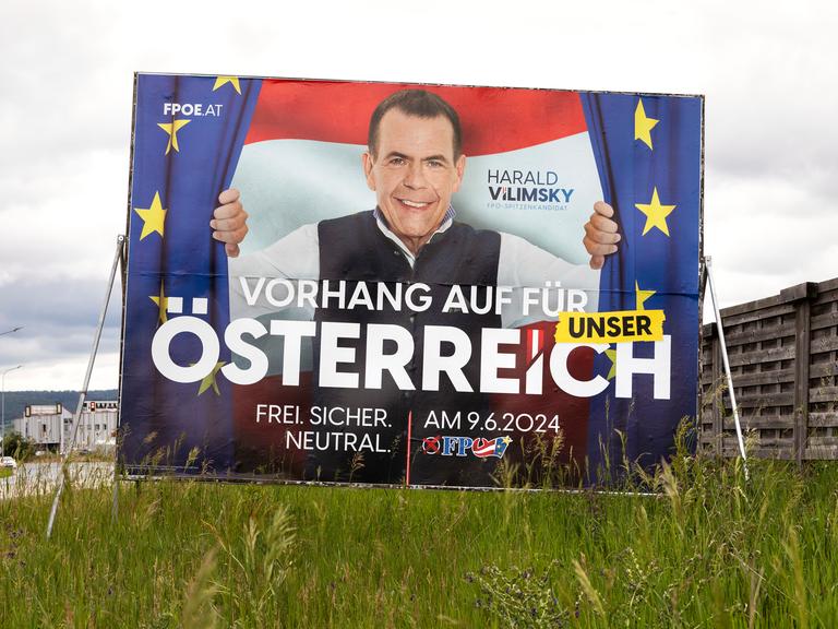 Ein Wahlplakat steht auf einer Wiese. Es zeigt Harald Vilimsky, der einen Vorhang mit dem EU-Emblem öffnet. 