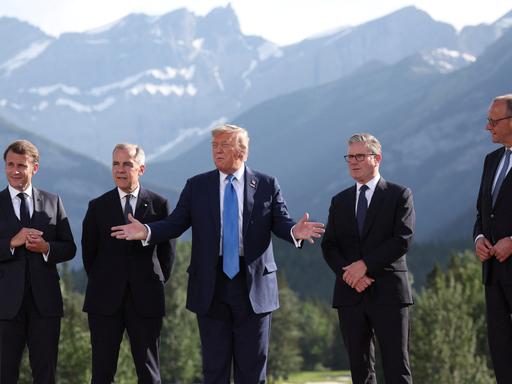 Emmanuel Macron, Mark Carney, Donald Trump, Keir Starmer und Friedrich Merz stehen vor den Bergen Alaskas beim G7-Gipfel zusammen
