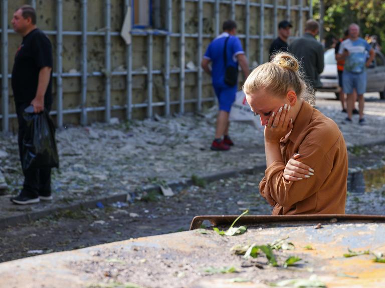 Eine Frau in Trauer neben einem zerstörten Auto in Kursk. 