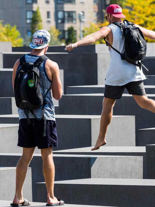 Touristen springen auf den Stehlen des Holocaust-Mahnmal der Stiftung Denkmal für die ermordeten Juden Europas herum, in Berlin Mitte.