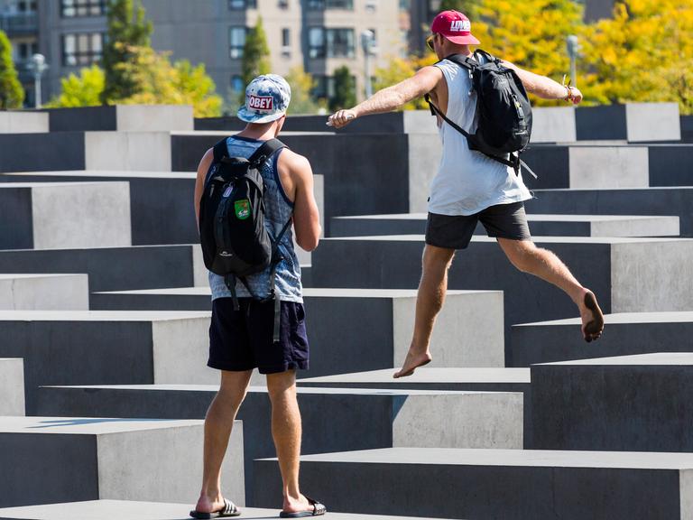 Touristen springen auf den Stehlen des Holocaust-Mahnmal der Stiftung Denkmal für die ermordeten Juden Europas herum, in Berlin Mitte.