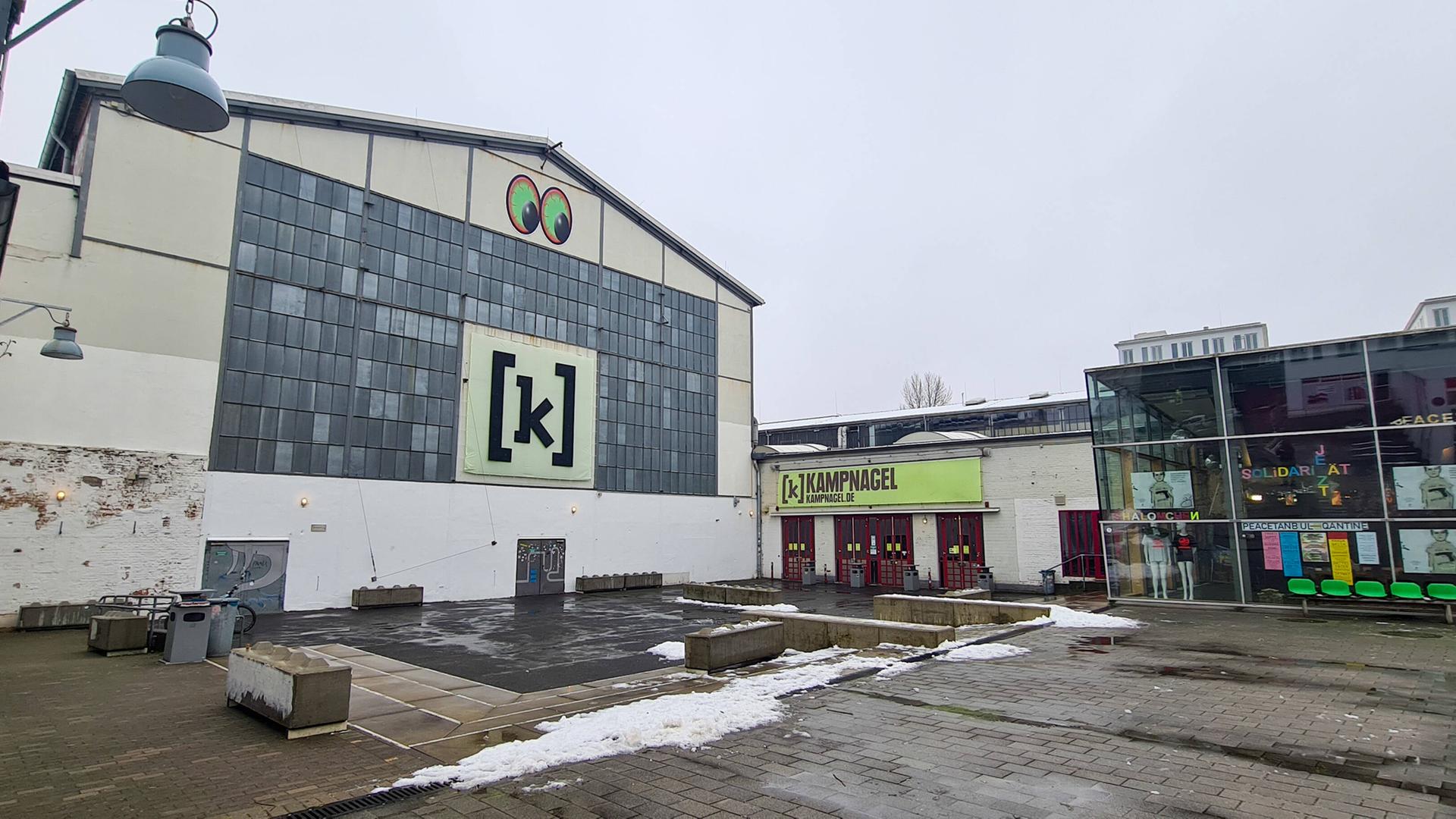 Außenaufnahme eines Fabrikgebäudes mit zwei großen grünen Augen und dem Buchstaben K an der Fassade
