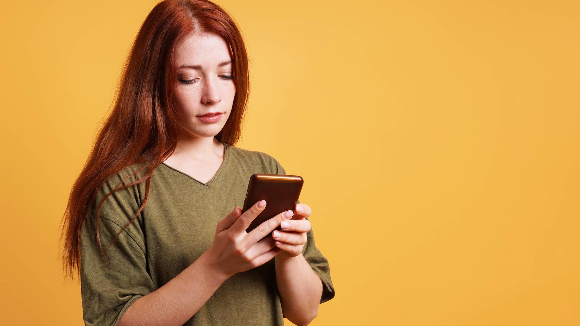 Junge Frau, die etwas auf ihrem Smartphone liest Junge Frau, die etwas auf ihrem Smartphone liest