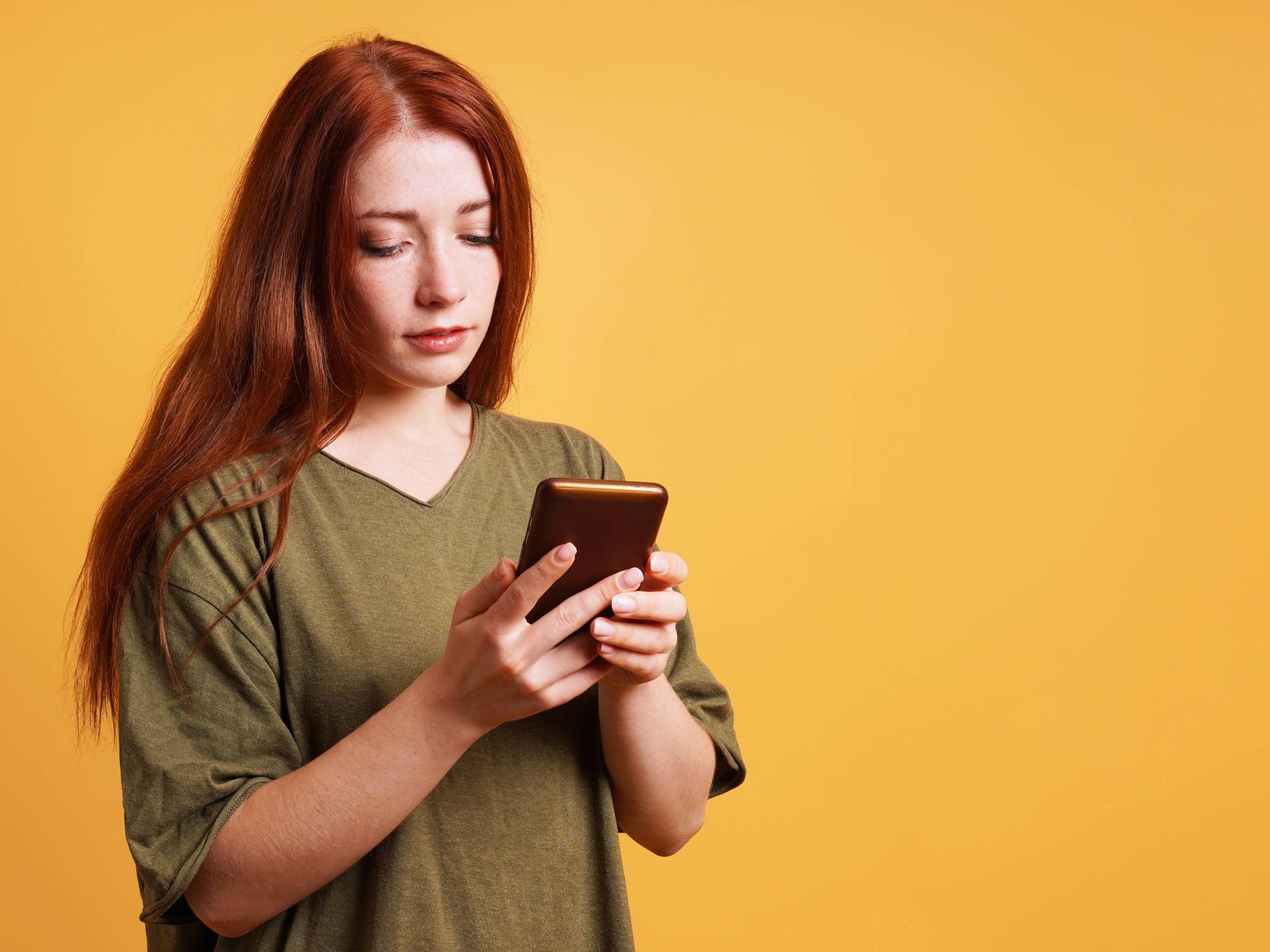 Junge Frau, die etwas auf ihrem Smartphone liest