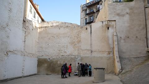 Menschen stehen bei einer Gedenkveranstaltung für die Opfer des Hauseinsturzes in Marseille in der Rue d'Aubagne an dem Platz, wo einmal zwei Häuser waren.