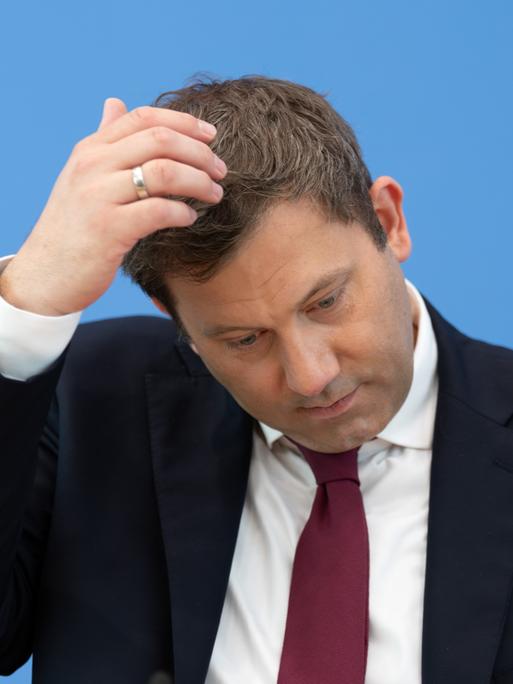Lars Klingbeil (SPD), Bundesminister der Finanzen, bei einer Pressekonferenz. Er kratzt sich am Kopf. Der Hintergrund ist blau.