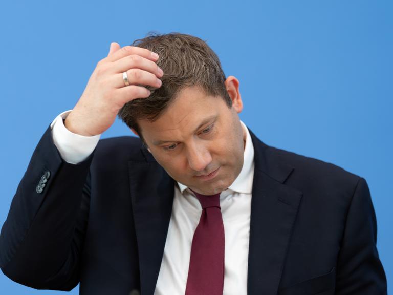 Lars Klingbeil (SPD), Bundesminister der Finanzen, bei einer Pressekonferenz. Er kratzt sich am Kopf. Der Hintergrund ist blau.