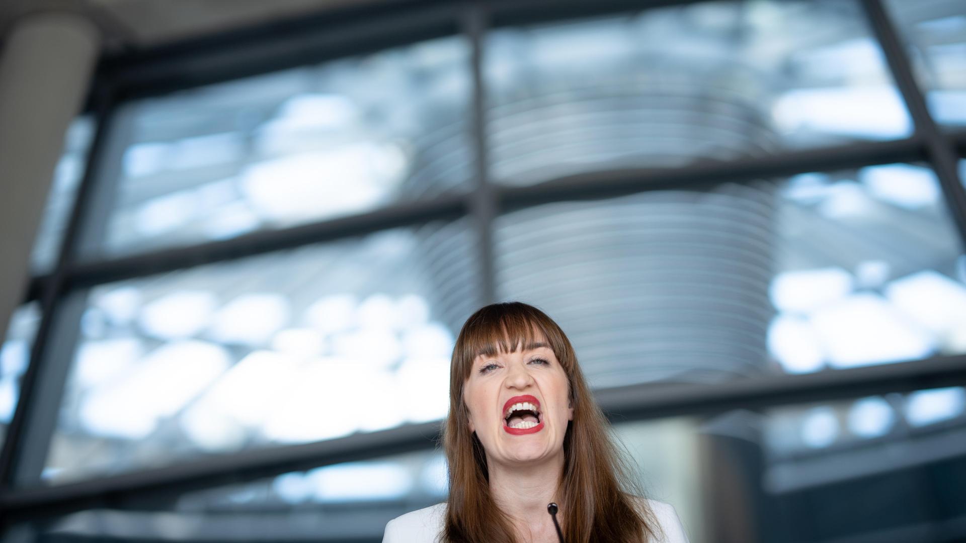 Heidi Reichinnek, Fraktionsvorsitzende Die Linke, gibt vor einem unscharfen Hintergrund aus Glasscheiben ein Statement ab. Ihr Kopf ist klein in der unteren Bildhälfte zu sehen. Sie scheint etwas zu rufen oder laut auszusprechen. Heidi Reichinnek, Fraktionsvorsitzende Die Linke, gibt vor einem unscharfen Hintergrund aus Glasscheiben ein Statement ab. Ihr Kopf ist klein in der unteren Bildhälfte zu sehen. Sie scheint etwas zu rufen oder laut auszusprechen.