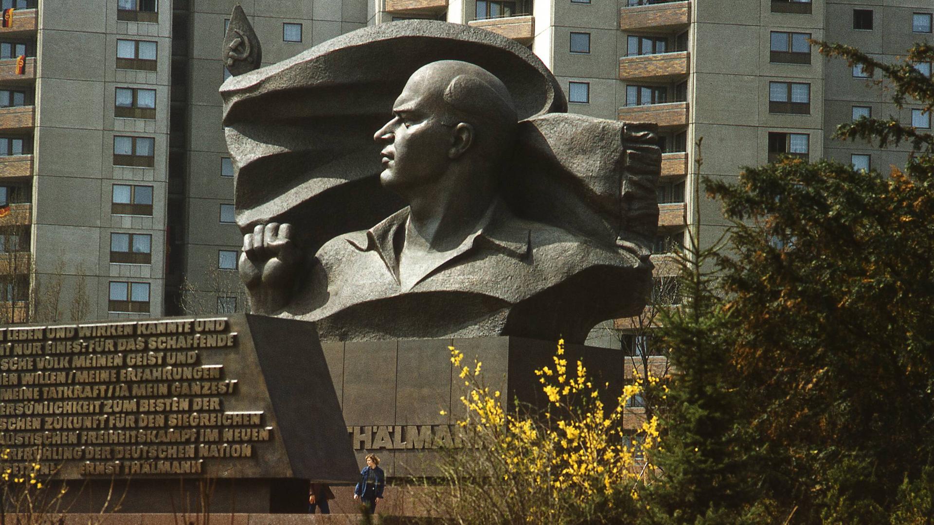 Das Ernst Thälmann Denkmal vor der Plattenbau-Kulisse in Berlin-Prenzlauer Berg. Im Vordergrund rote Blumen, im Hintergrund die Plattenbauten. Das Ernst Thälmann Denkmal vor der Plattenbau-Kulisse in Berlin-Prenzlauer Berg. Im Vordergrund rote Blumen, im Hintergrund die Plattenbauten.