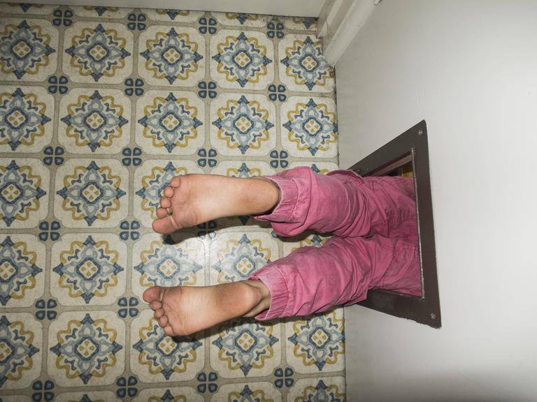 Kinderbeine die aus einer Türöffnung herausschauen.